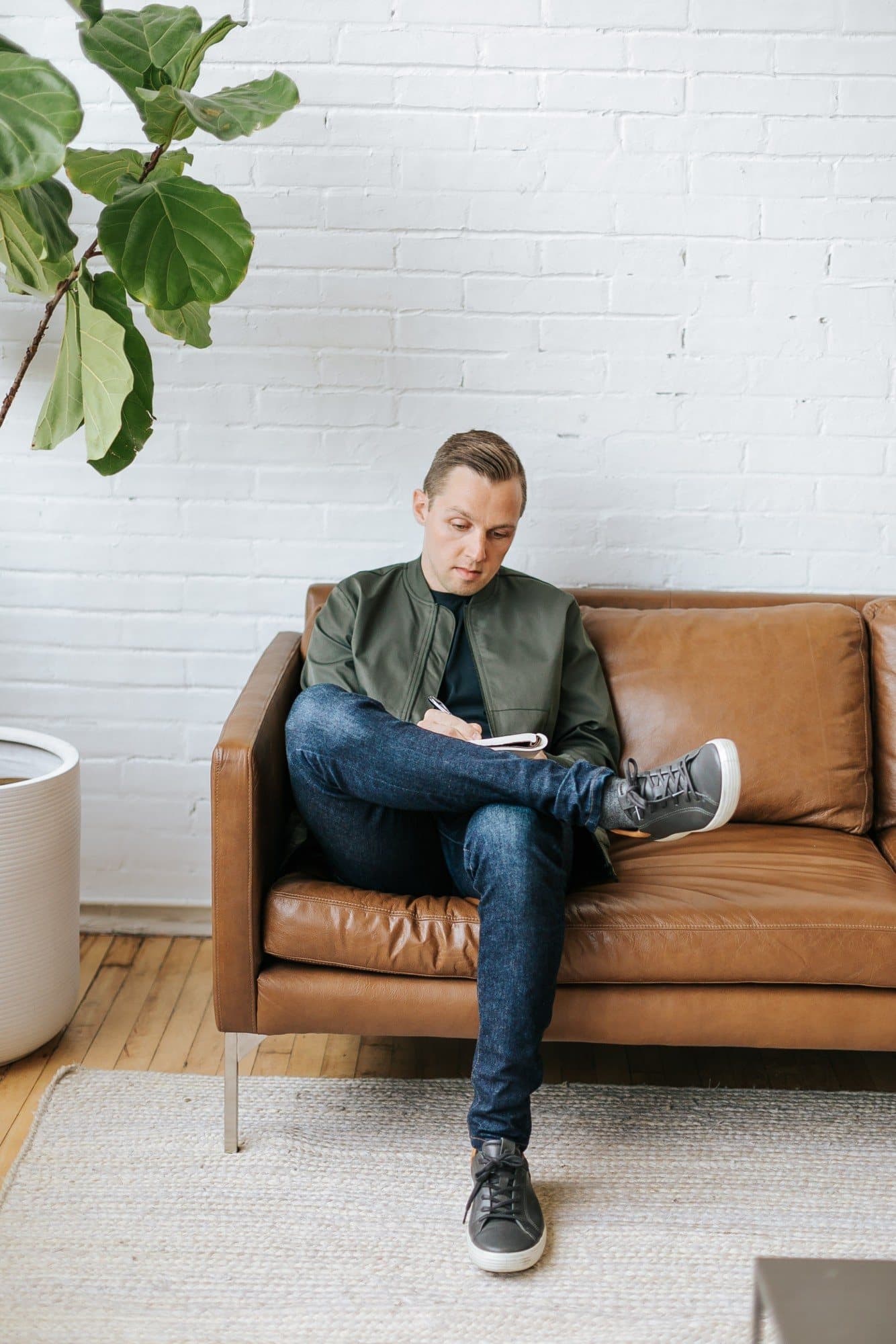 Evan Shoemaker sitting on a leather sofa, writing in a notebook