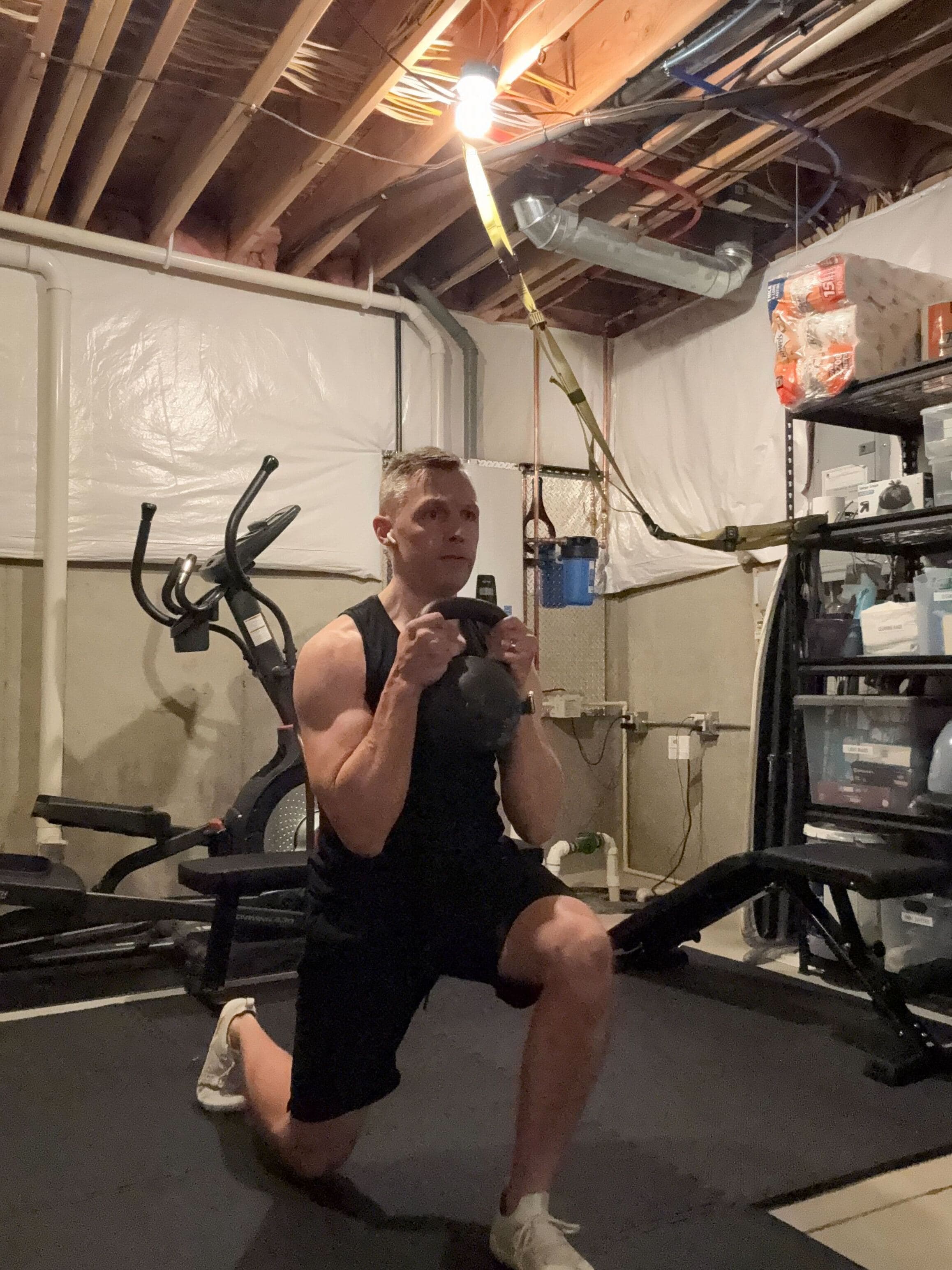 Evan doing a kettlebell lunge in his basement gym